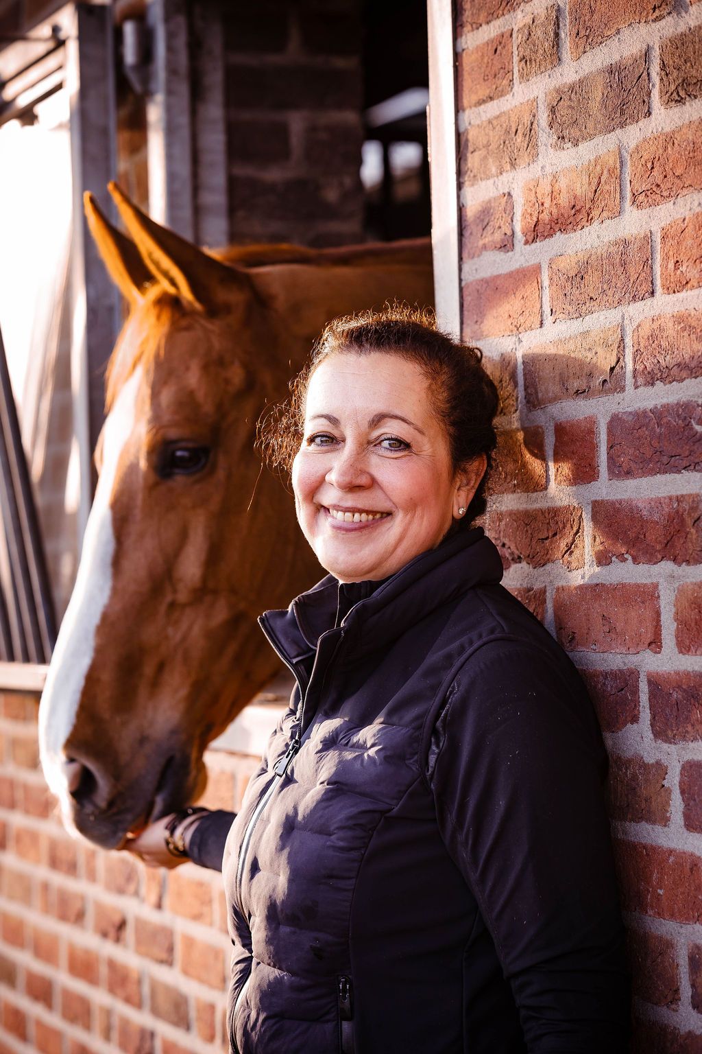 Jeannette lacht, met haar vos naast zich bij de bakstenen stal