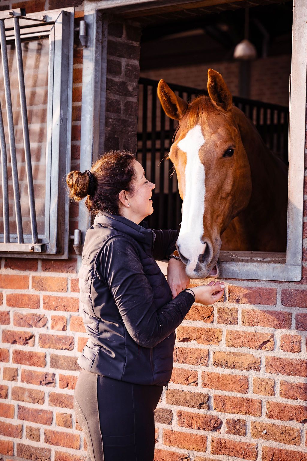 Jeannette staat bij de staldeur en kijkt haar vos rustig aan